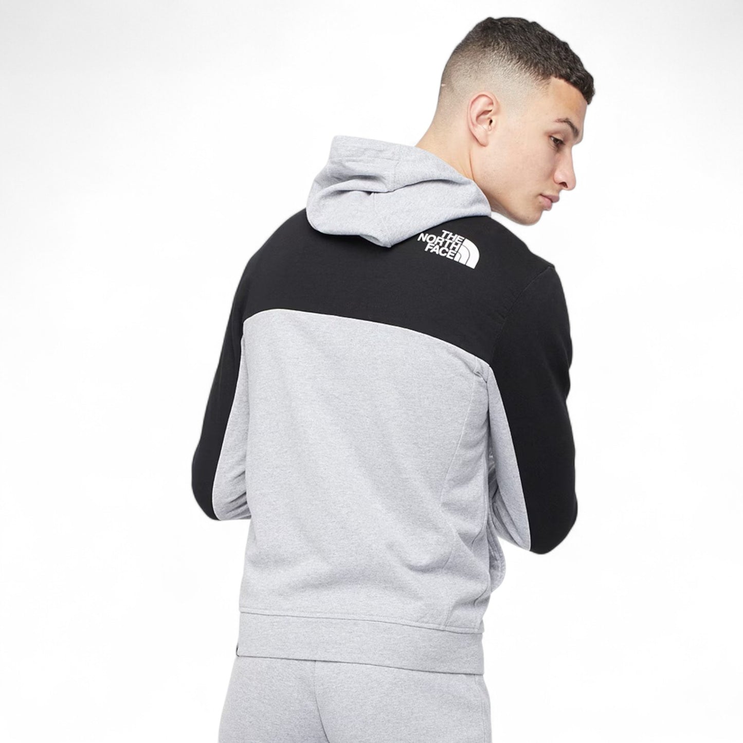 Person wearing a black and gray color-blocked hoodie with 'The North Face' logo on a white background