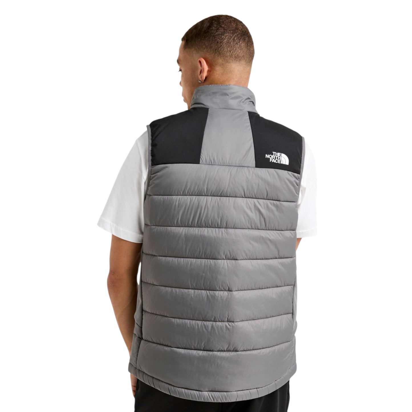 Person wearing a gray puffer vest with a brand logo on a white background