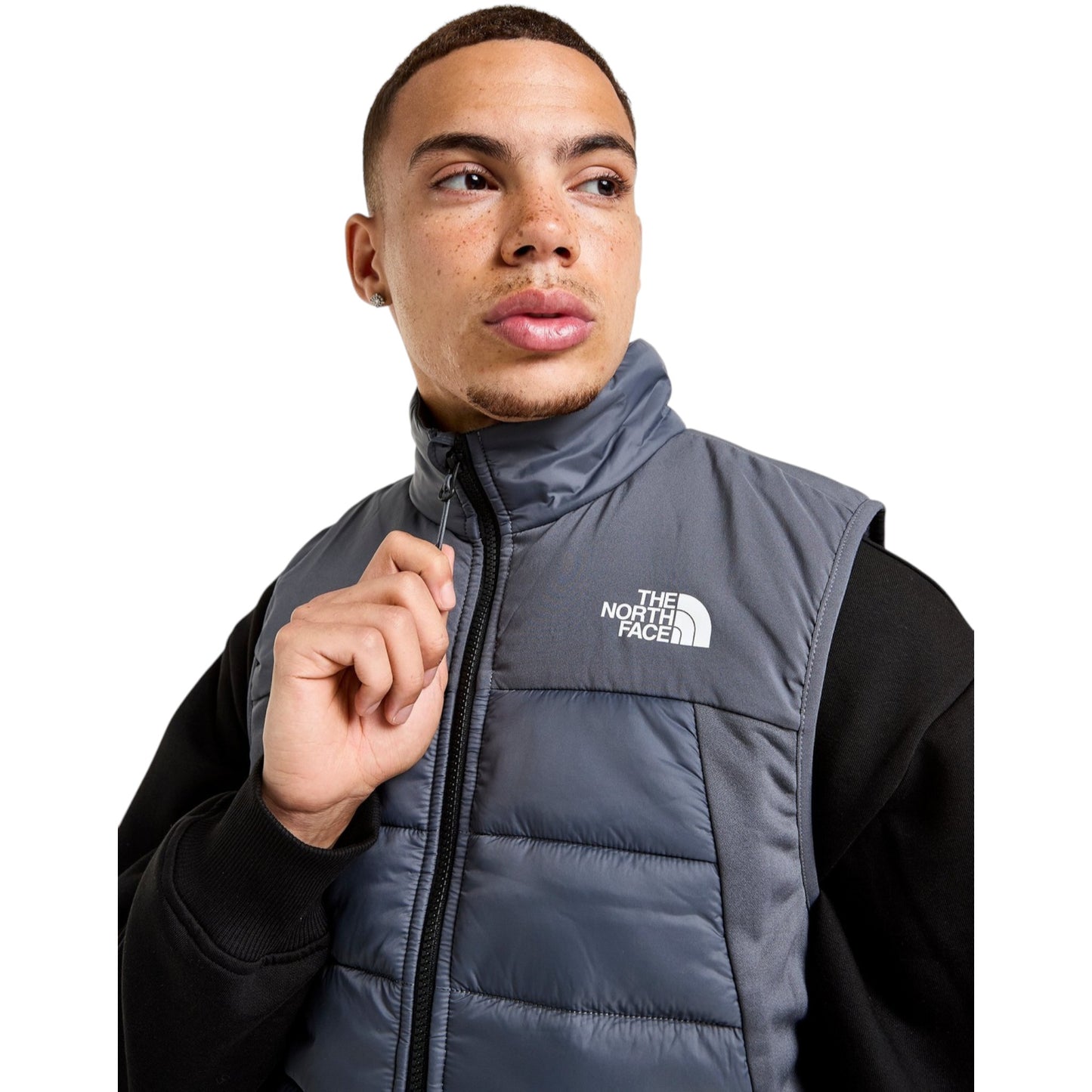 Person wearing a gray puffer vest with The North Face logo on a white background