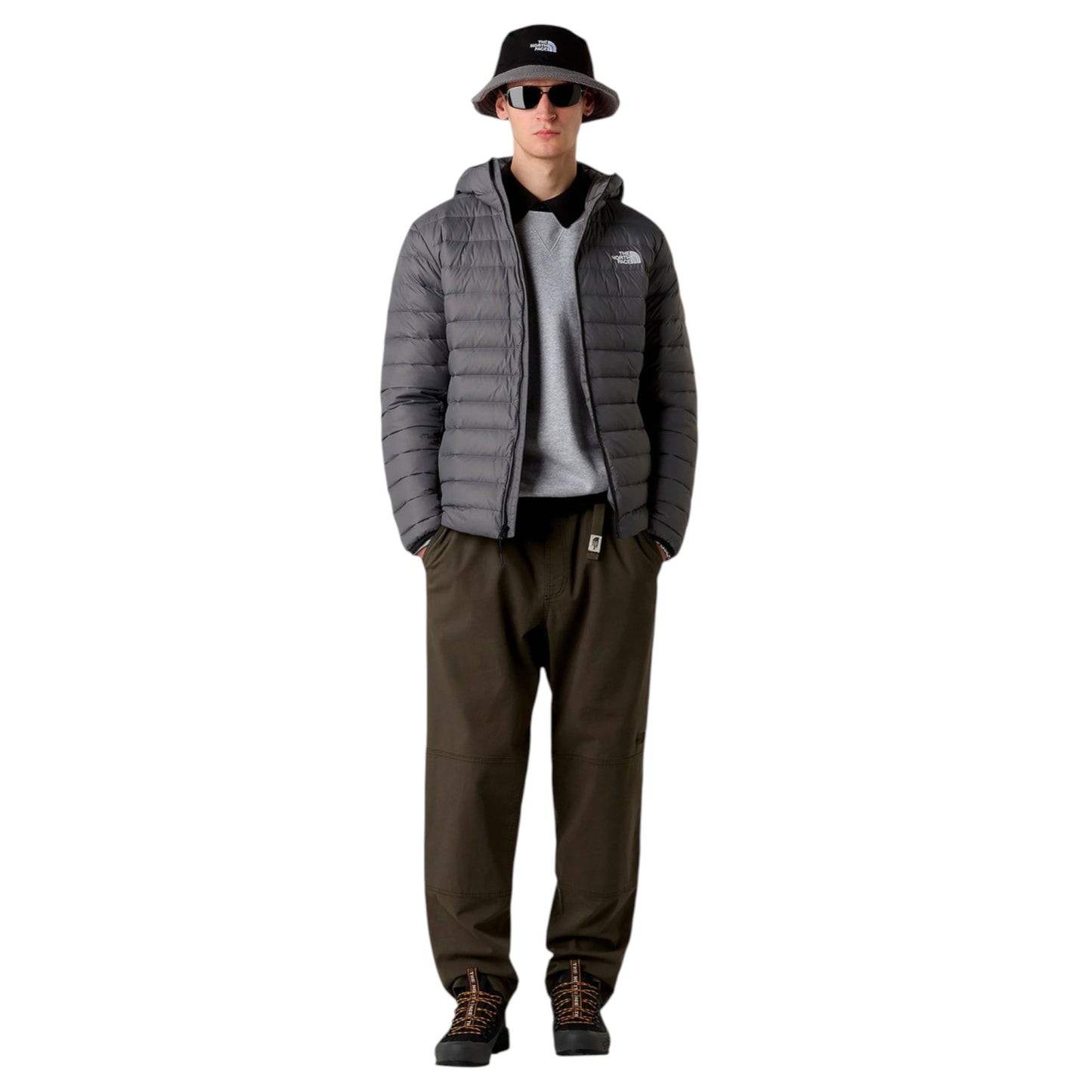 Person wearing a gray puffer jacket, black pants, and a black cap with a logo on a white background