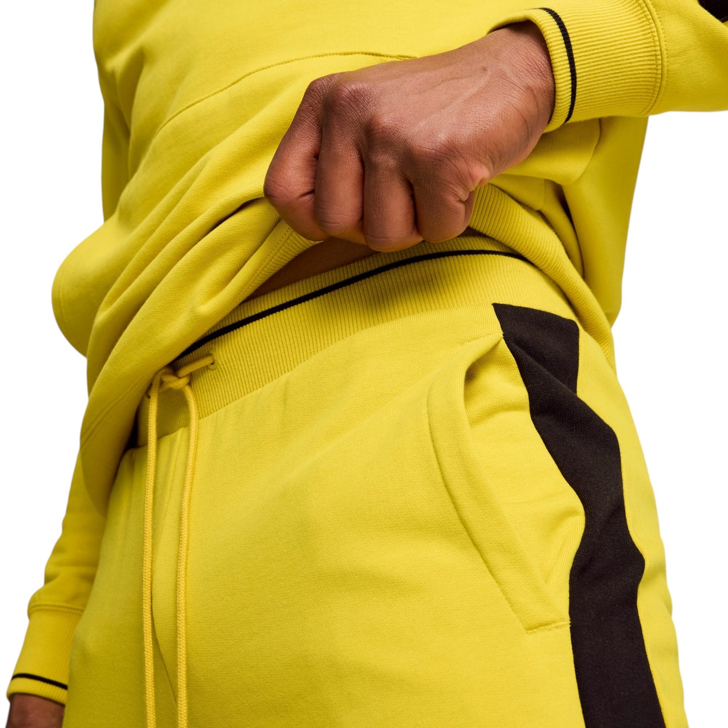 Person wearing a bright yellow tracksuit with a black stripe on a white background