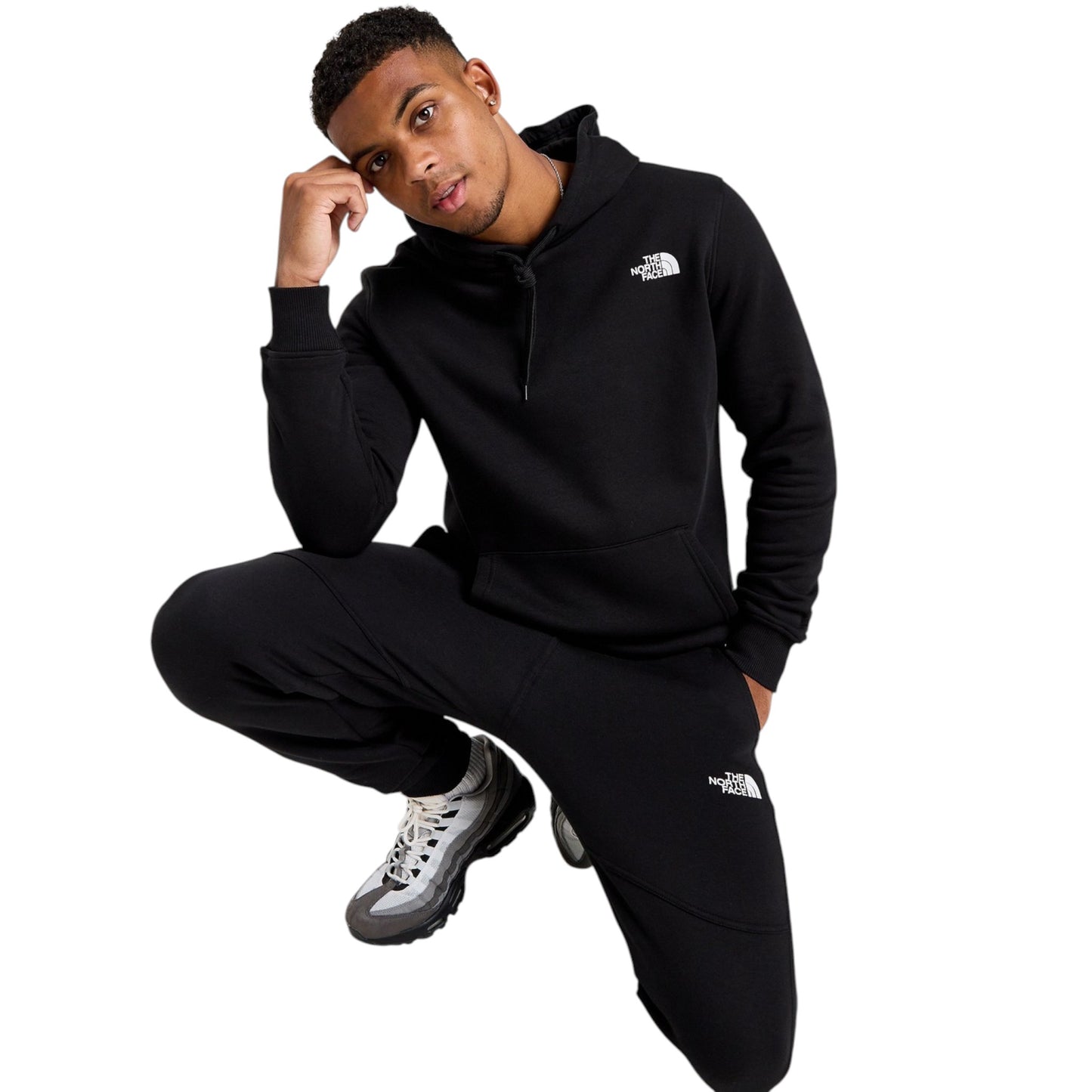 Person wearing a black hoodie and pants with a brand logo on a white background