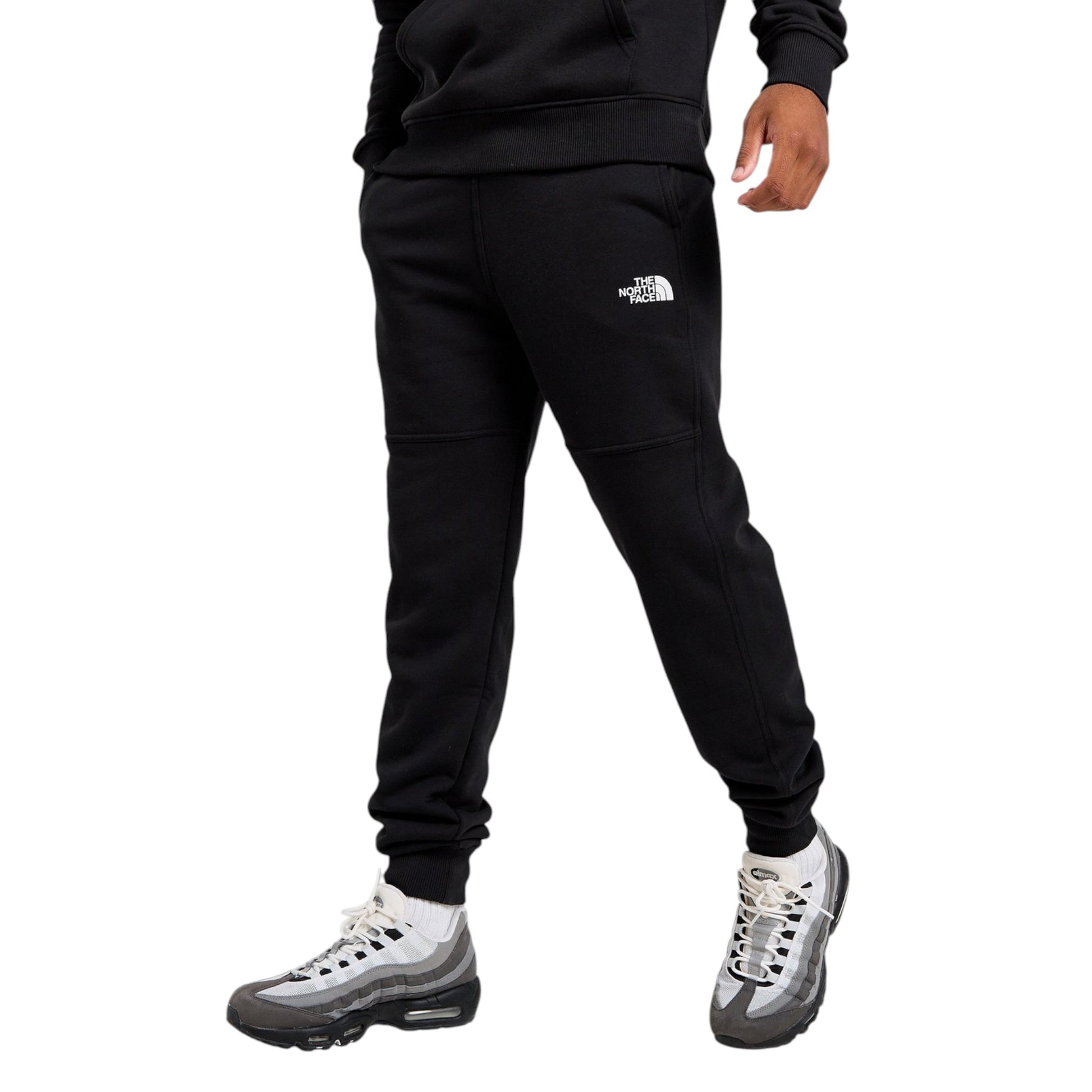 Person wearing black jogger pants with a brand logo on a white background