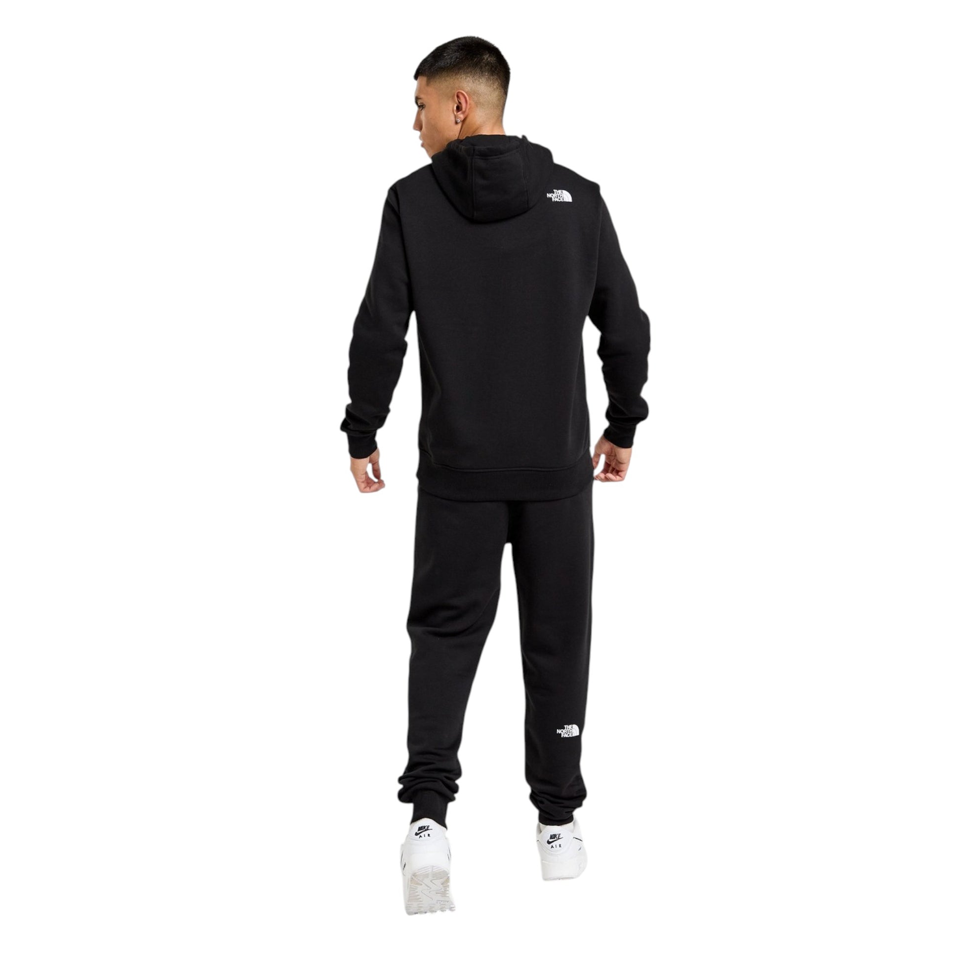 Person wearing a black tracksuit with a logo on the back, standing against a white background