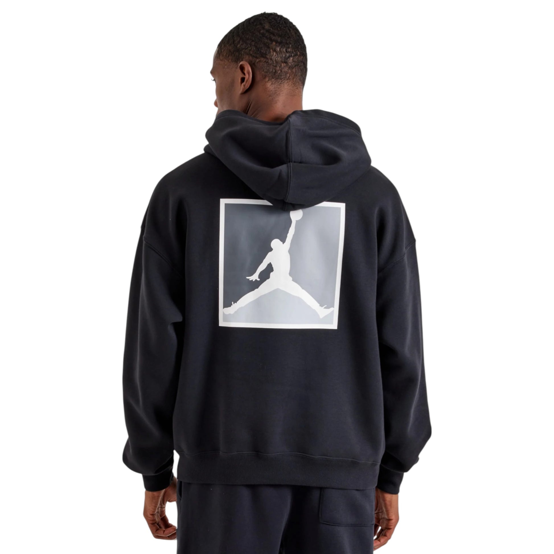 Person wearing a black hoodie with a white logo on the back, standing against a white background