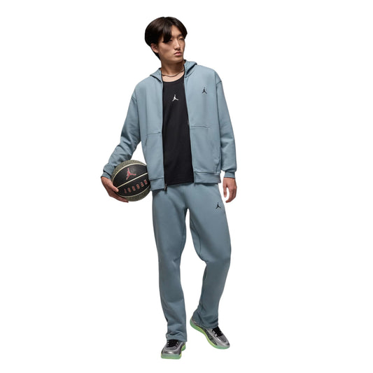 Person wearing a gray tracksuit holding a basketball on a white background