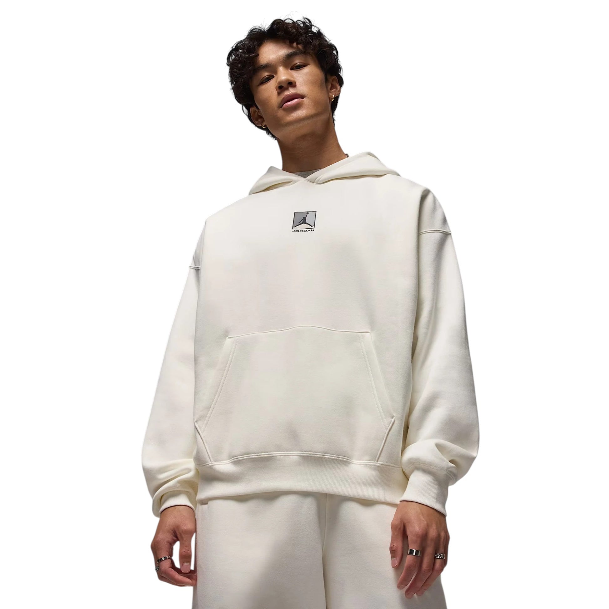 Person wearing a white hoodie with a small logo on a white background