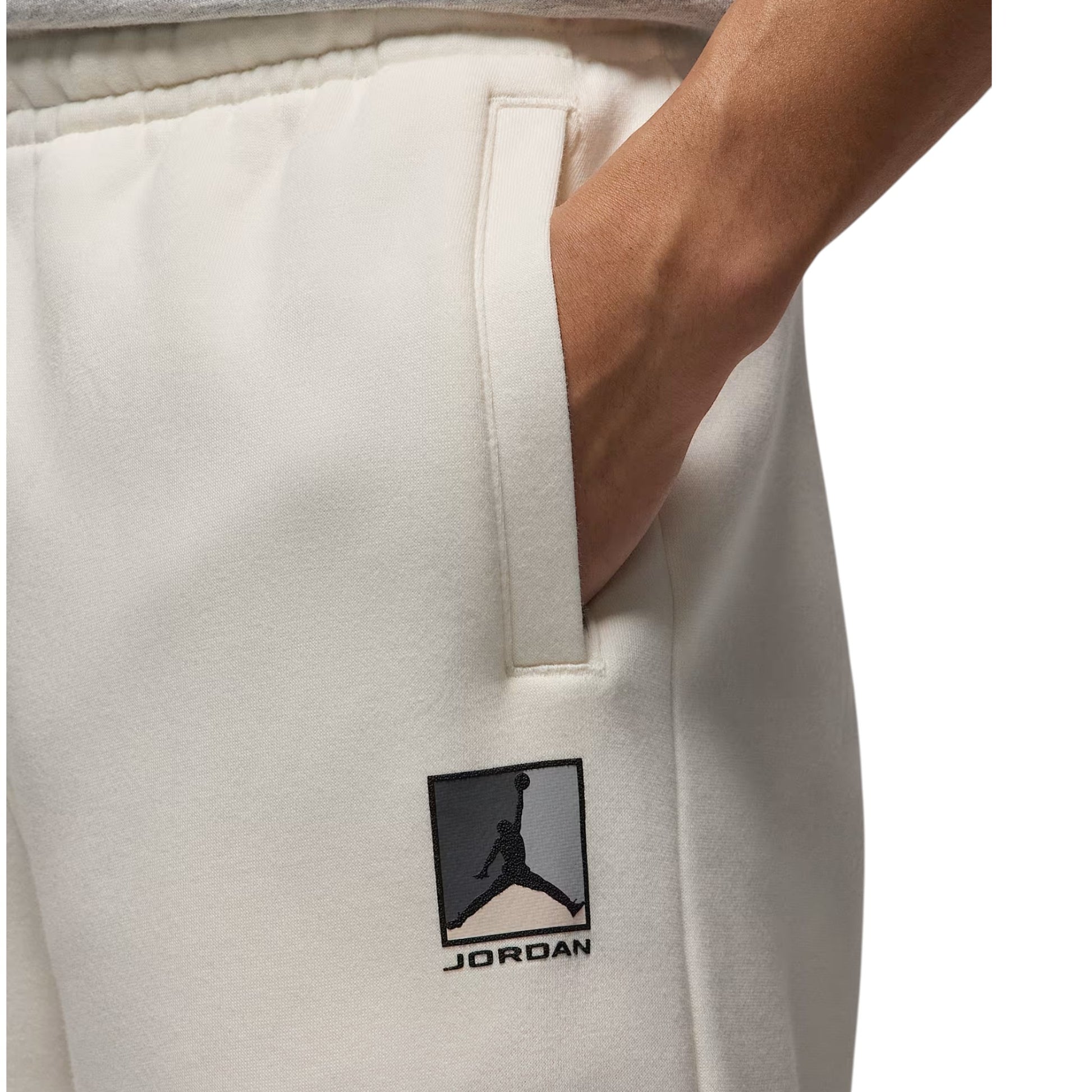 White sweatpants with a Jordan logo on the pocket against a neutral background