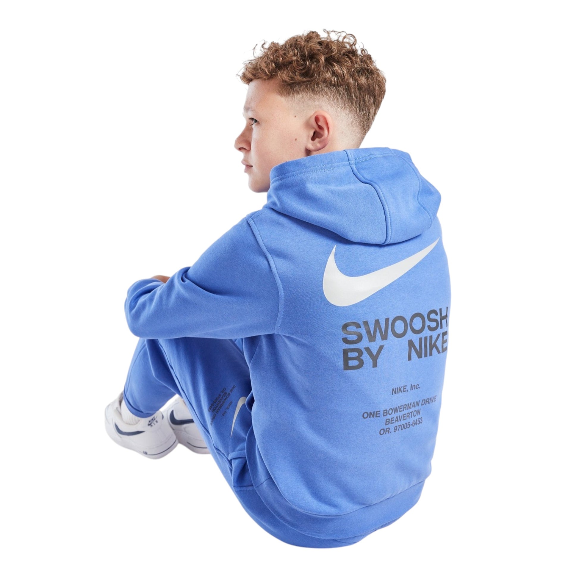 Person wearing a blue Nike hoodie with text sitting on the floor.