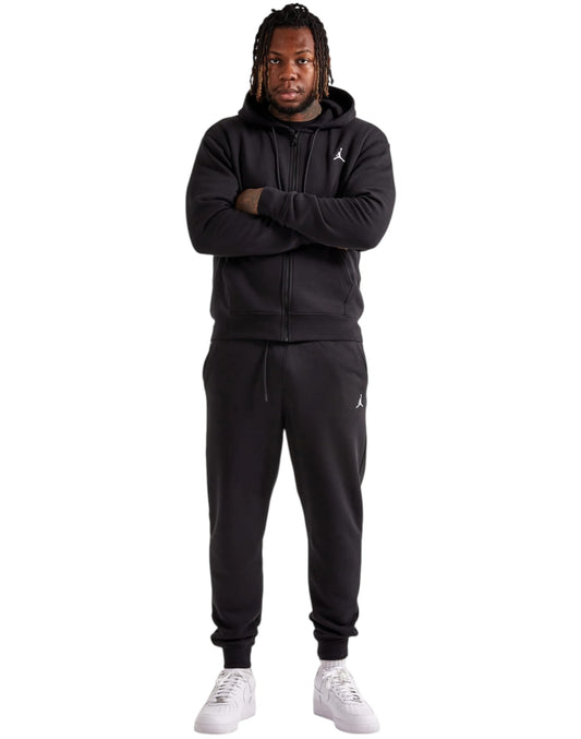 Person wearing a black Jordan tracksuit on a white background