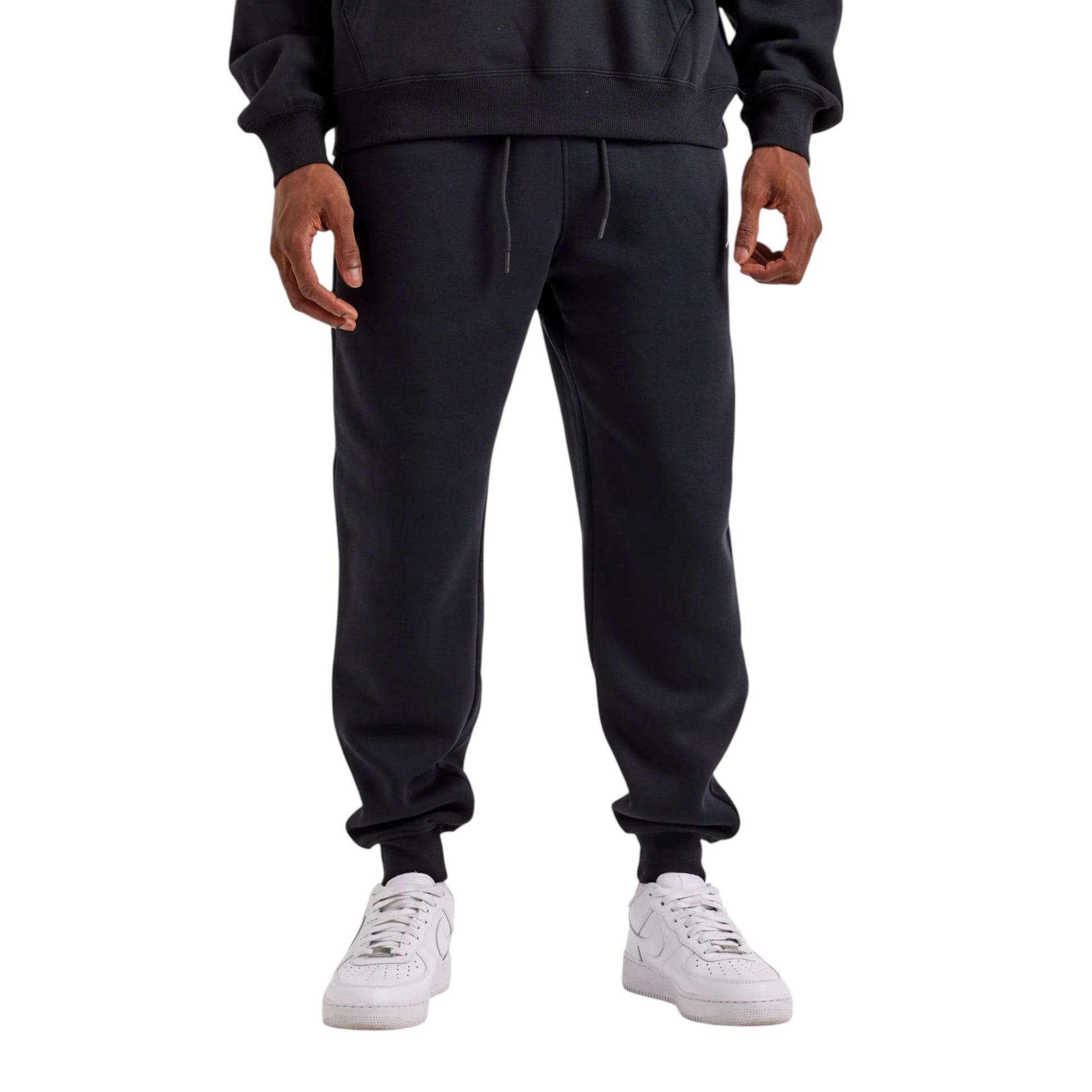 Person wearing black sweatpants and white sneakers on a white background