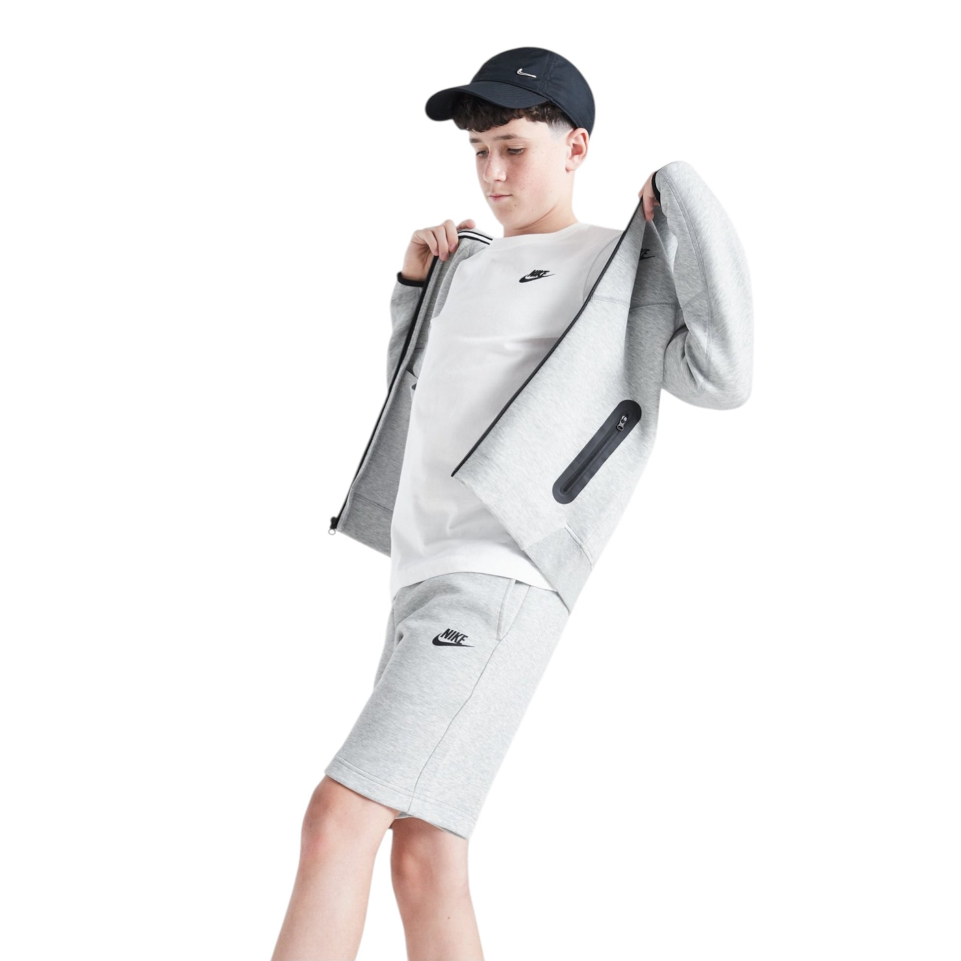 Person wearing a gray Nike tracksuit and cap on a white background