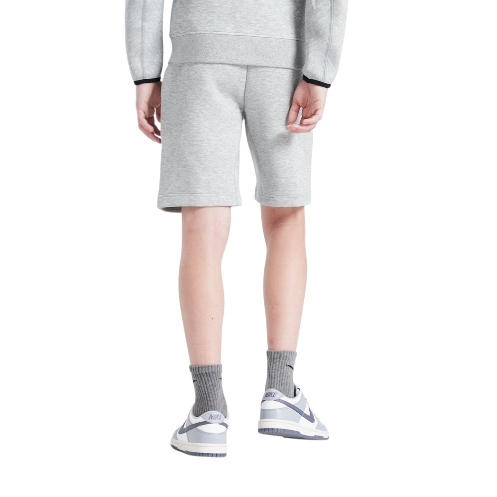 Person wearing a gray tracksuit with shorts on a white background
