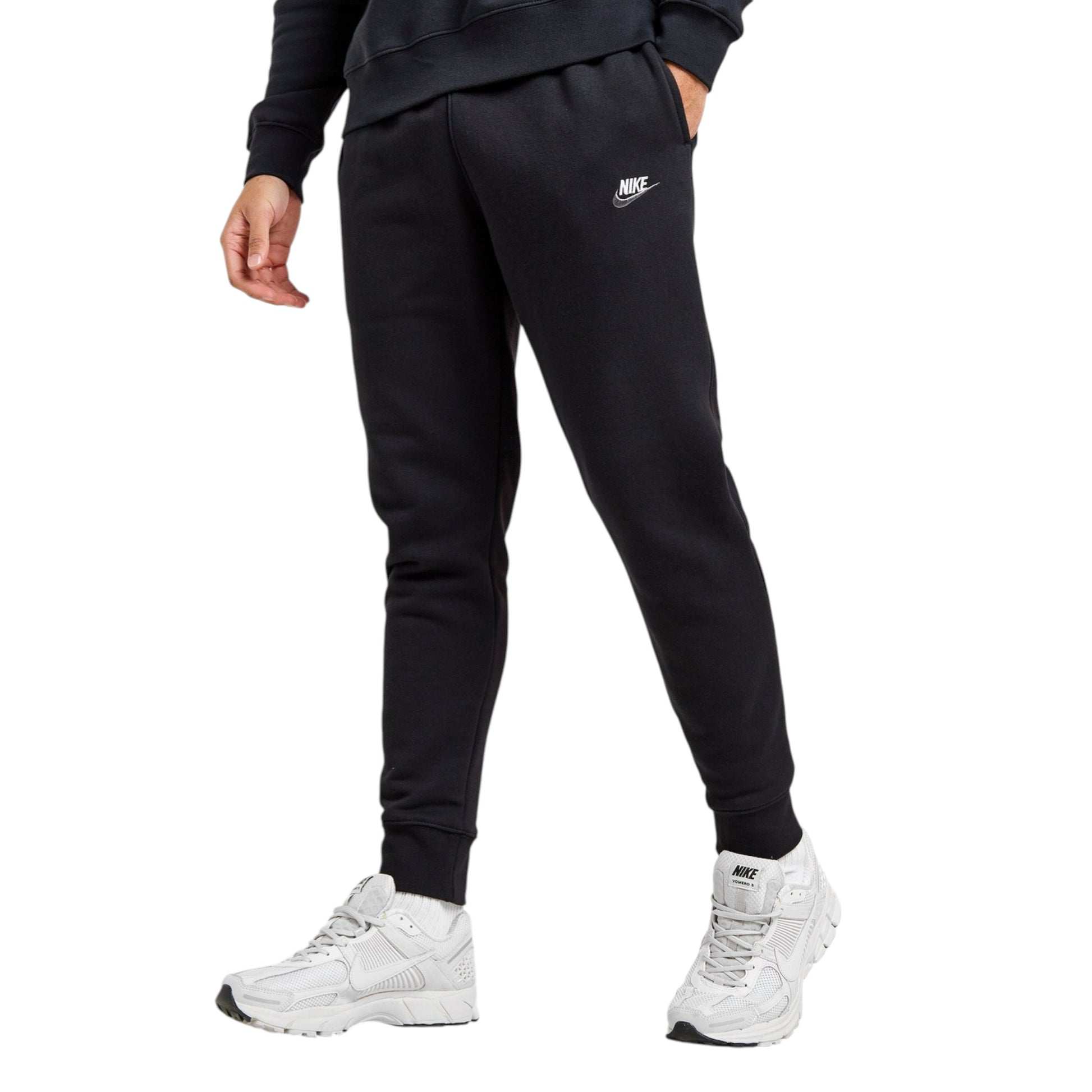 Person wearing black Nike sweatpants and white sneakers on a white background