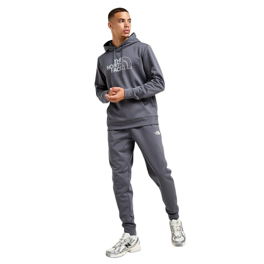 Person wearing a gray hoodie and pants with a brand logo on a white background