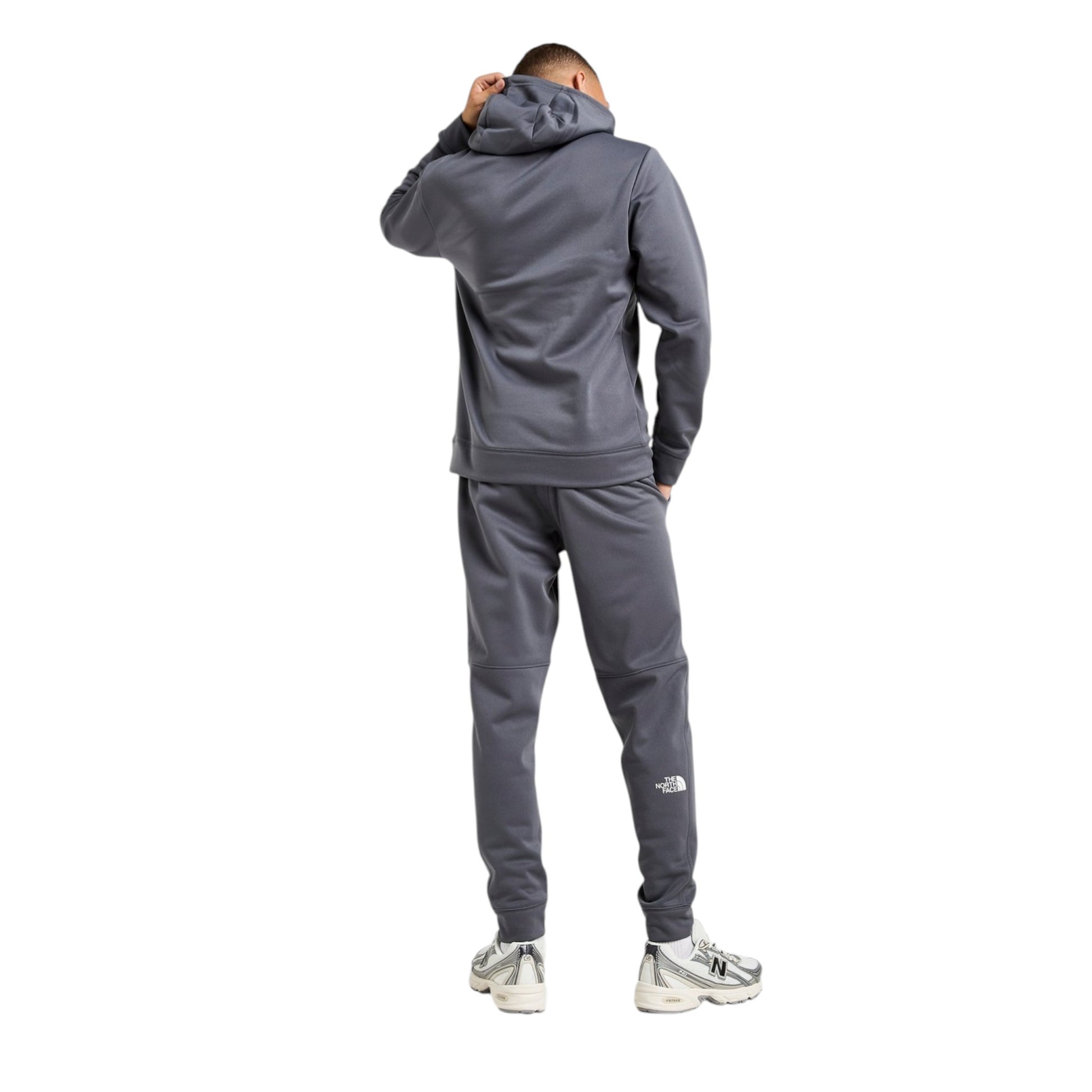 Person wearing a gray tracksuit with a brand logo on a white background