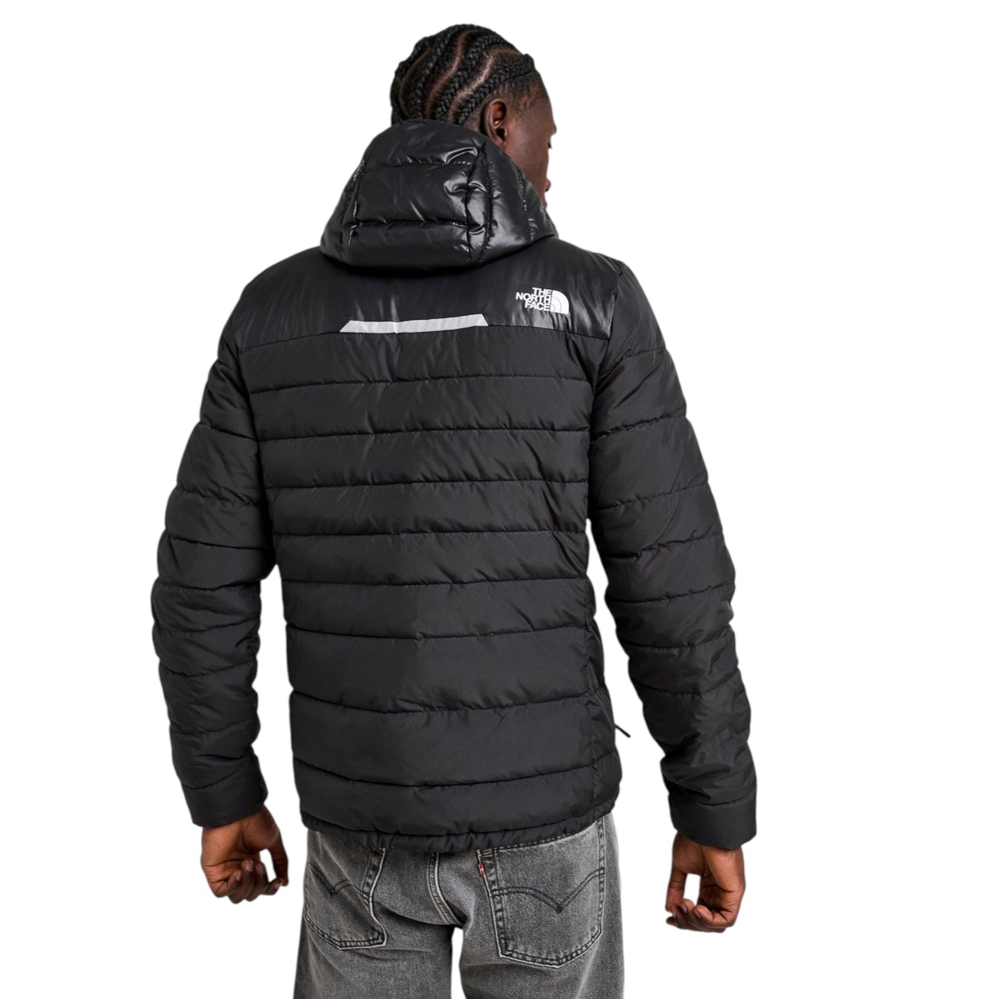 Person wearing a black puffer jacket with a brand logo on the back, standing against a white background.