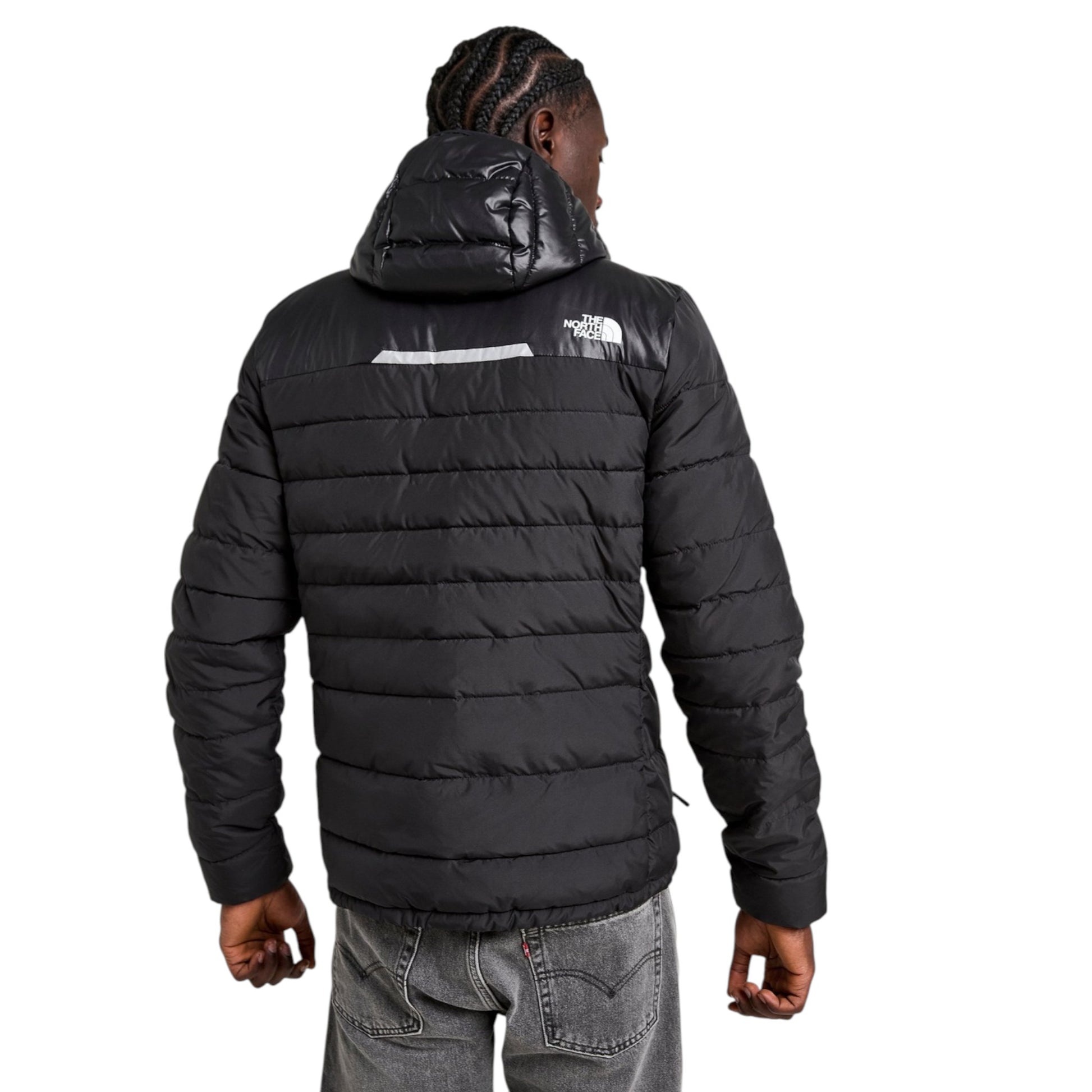 Person wearing a black puffer jacket with a brand logo on the back, standing against a white background.