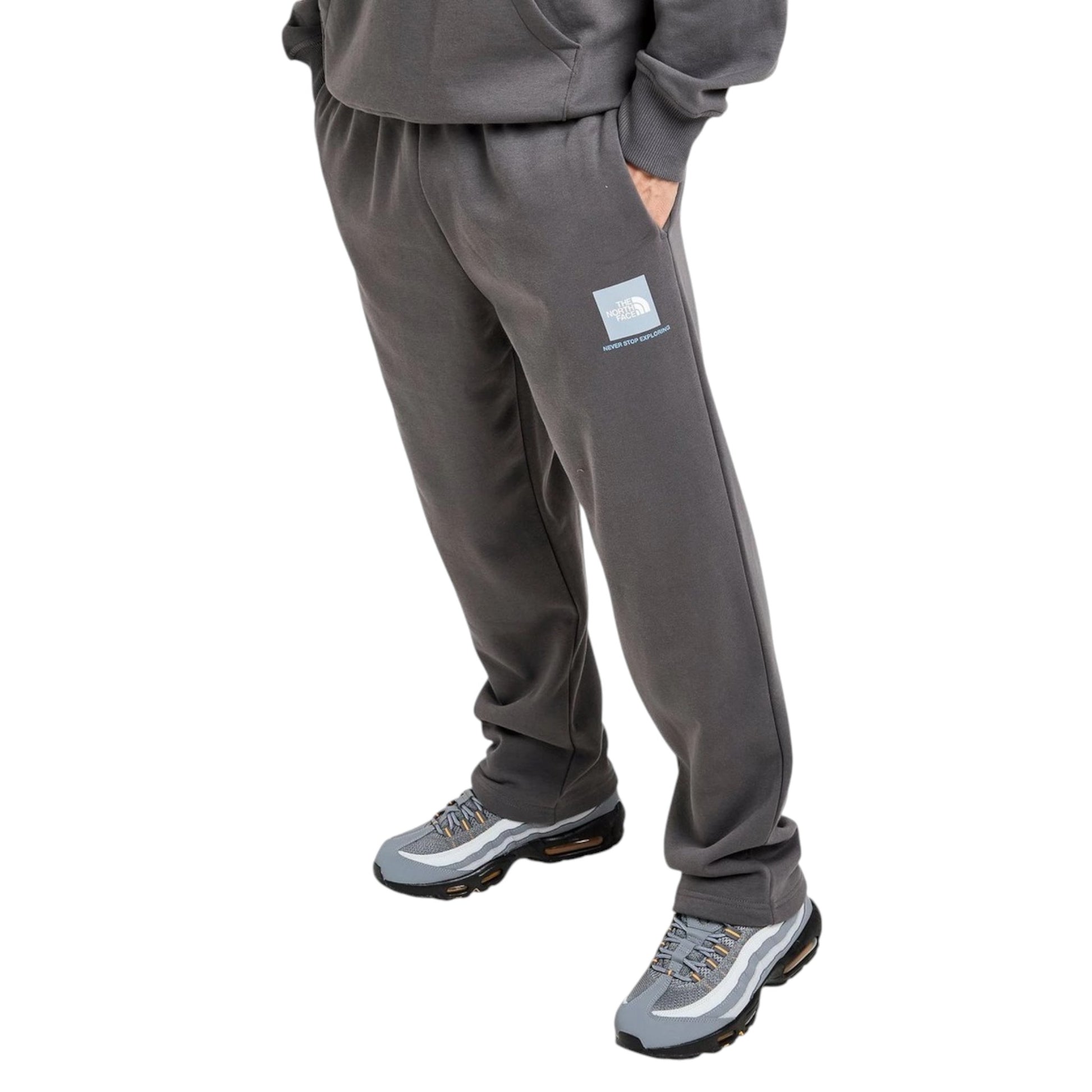 Person wearing gray tracksuit with a logo on a white background