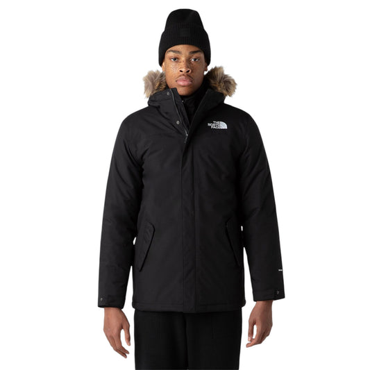 Person wearing a black winter jacket with fur hood on a white background