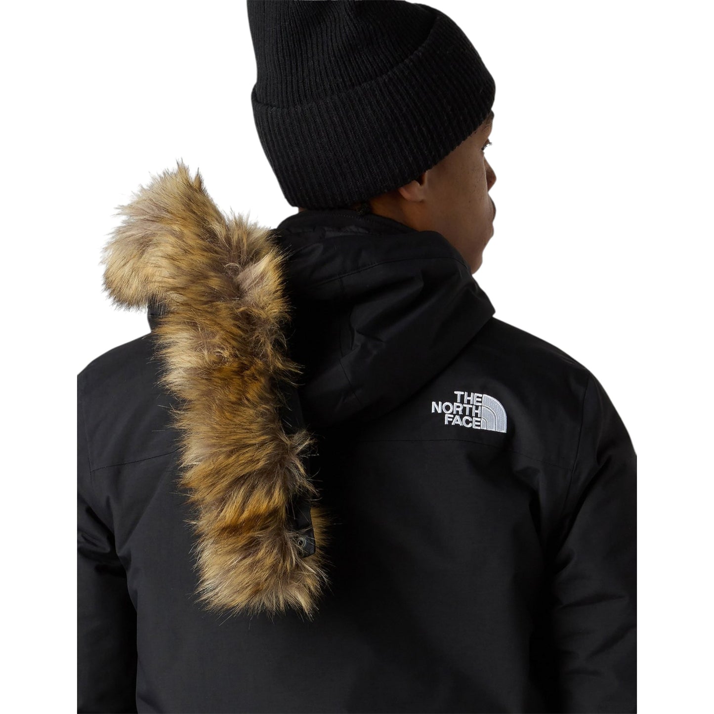 Person wearing a black North Face jacket with fur-lined hood on a white background