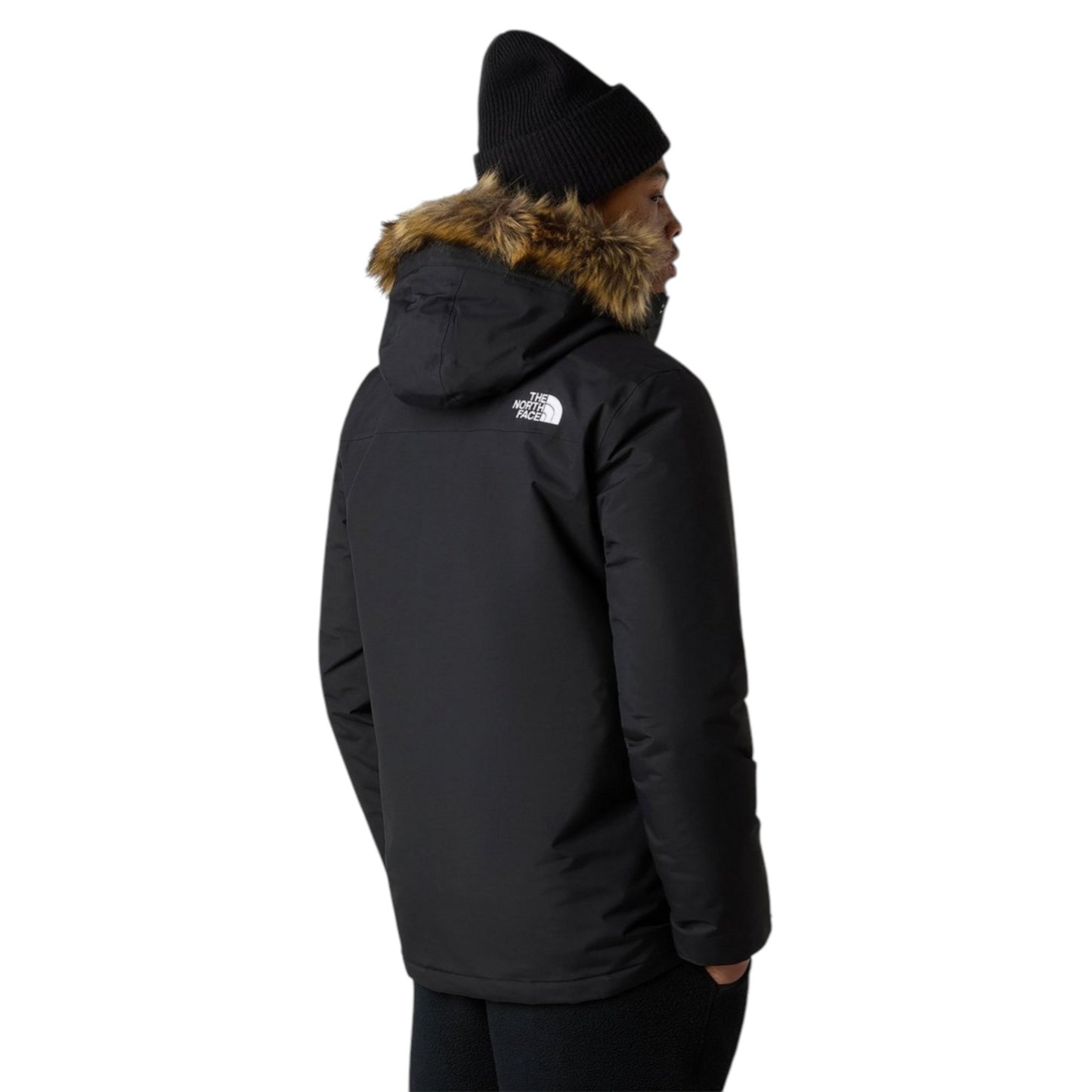 Person wearing a black winter jacket with fur hood and The North Face logo on a white background