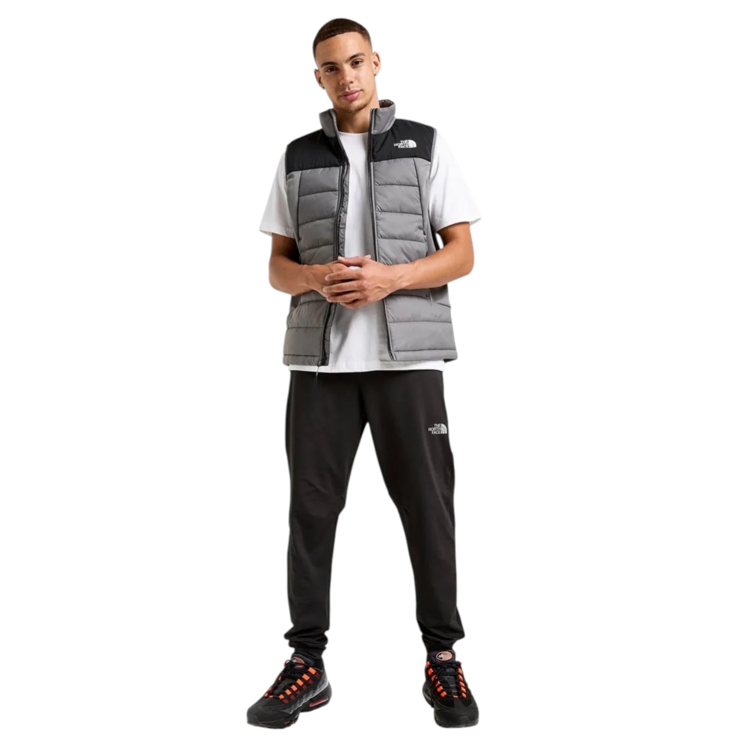 Person wearing a gray vest over a white shirt with black pants on a white background
