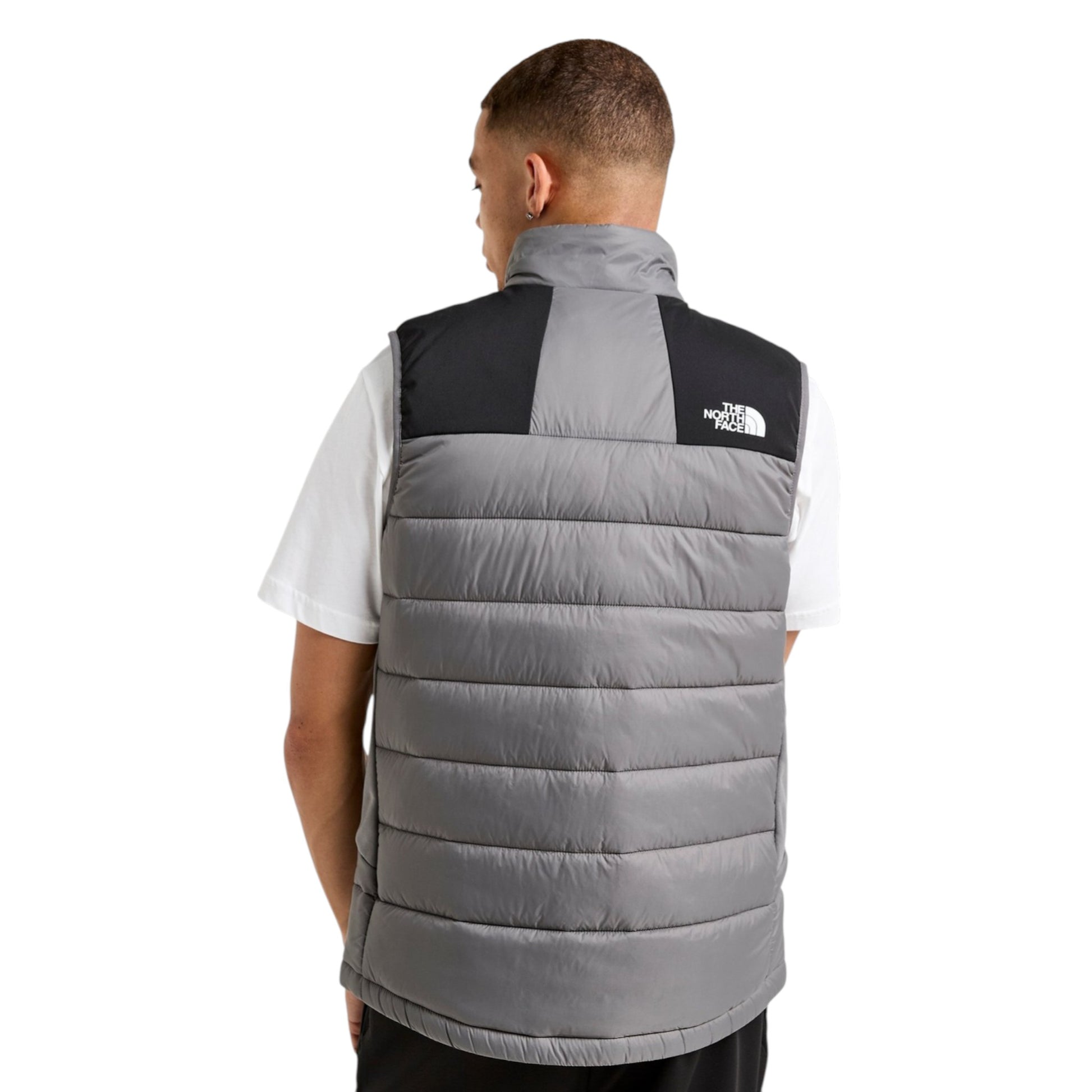 Person wearing a gray puffer vest with a brand logo on a white background