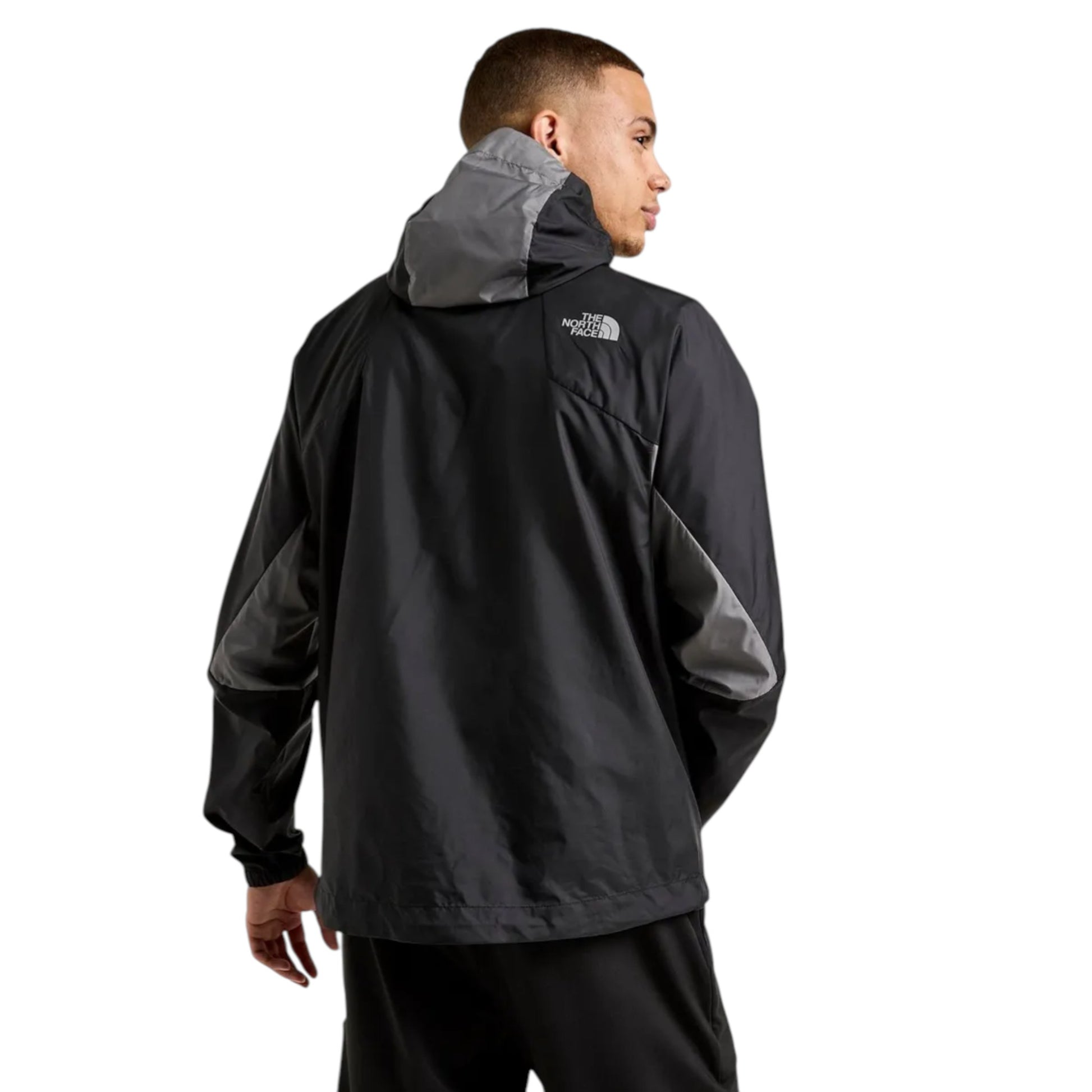 Person wearing a black and gray jacket with The North Face logo on a white background