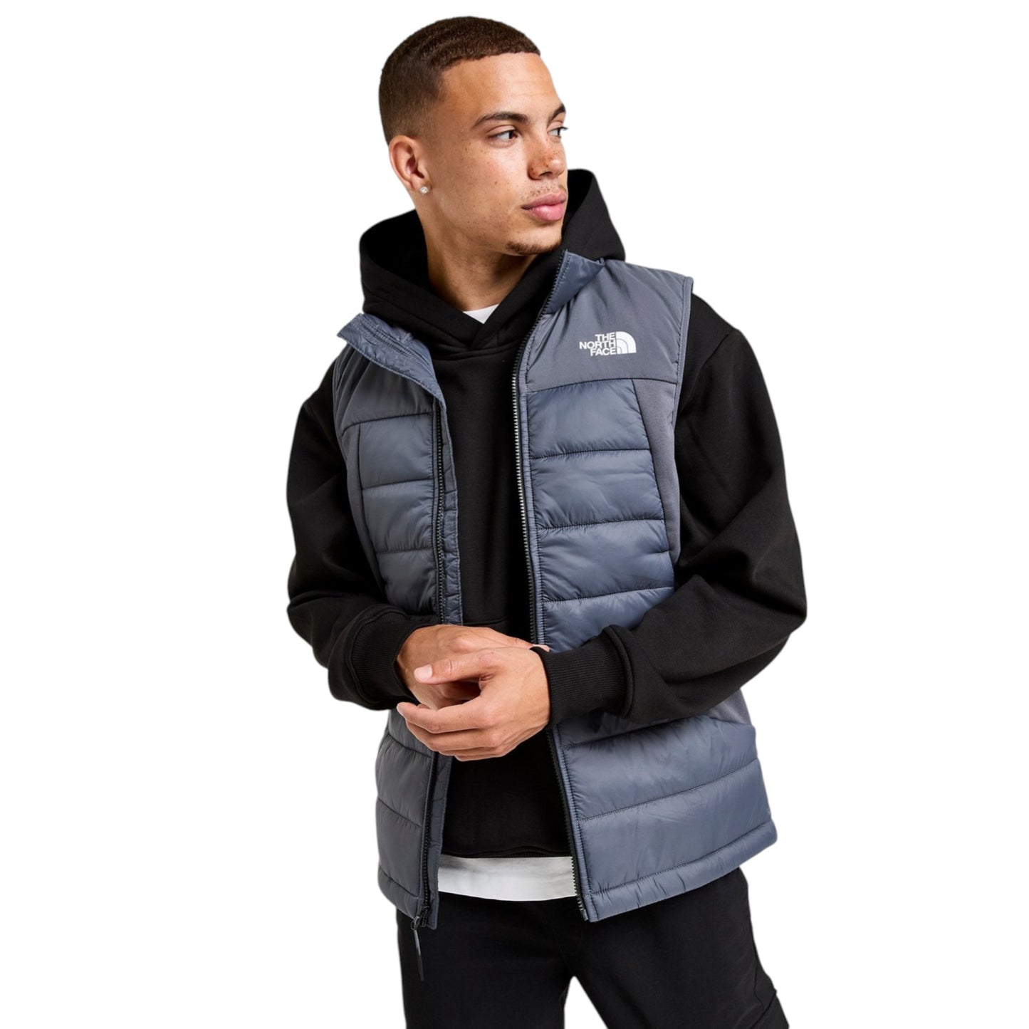 Man wearing a gray puffer vest over a black hoodie on a white background