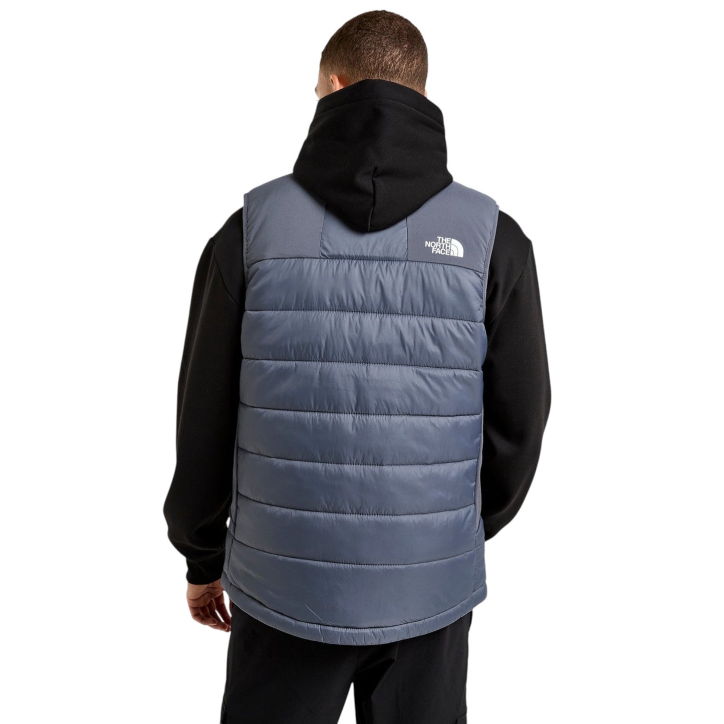 Person wearing a blue puffer vest with a black hood on a white background