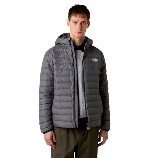 Person wearing a gray puffer jacket with a brand logo on a white background