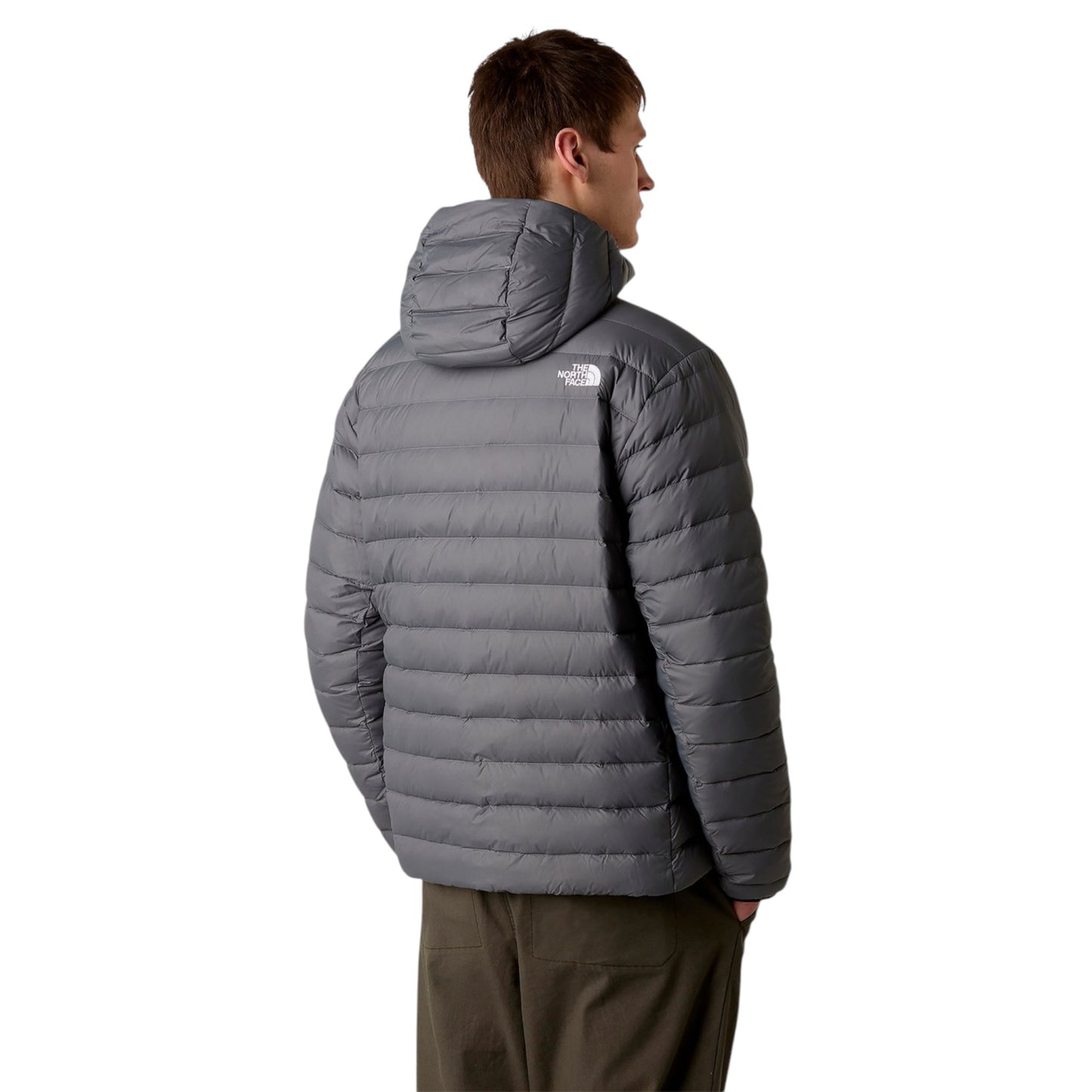 Person wearing a gray puffer jacket with a hood on a white background