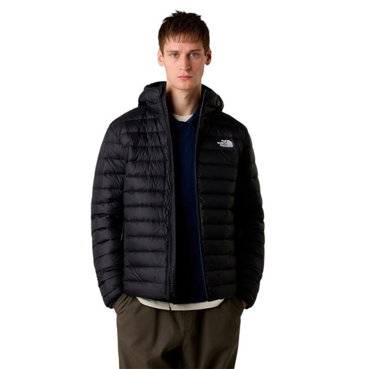 Person wearing a black puffer jacket with a brand logo on a white background