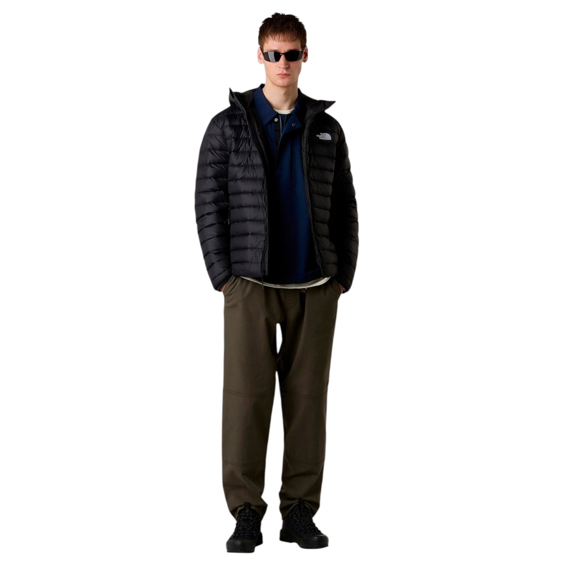 Man wearing a black puffer jacket and sunglasses on a white background