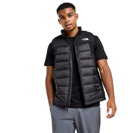 Man wearing a black puffer vest over a black shirt on a white background