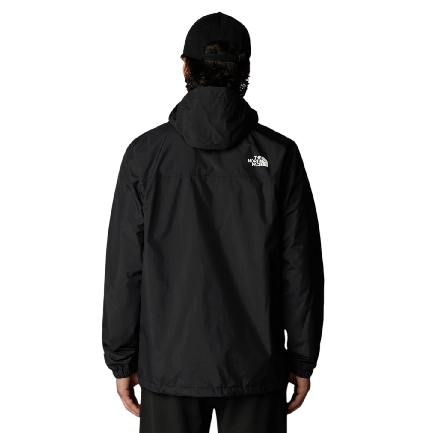 Person wearing a black jacket with a visible brand logo on the back, standing against a white background.