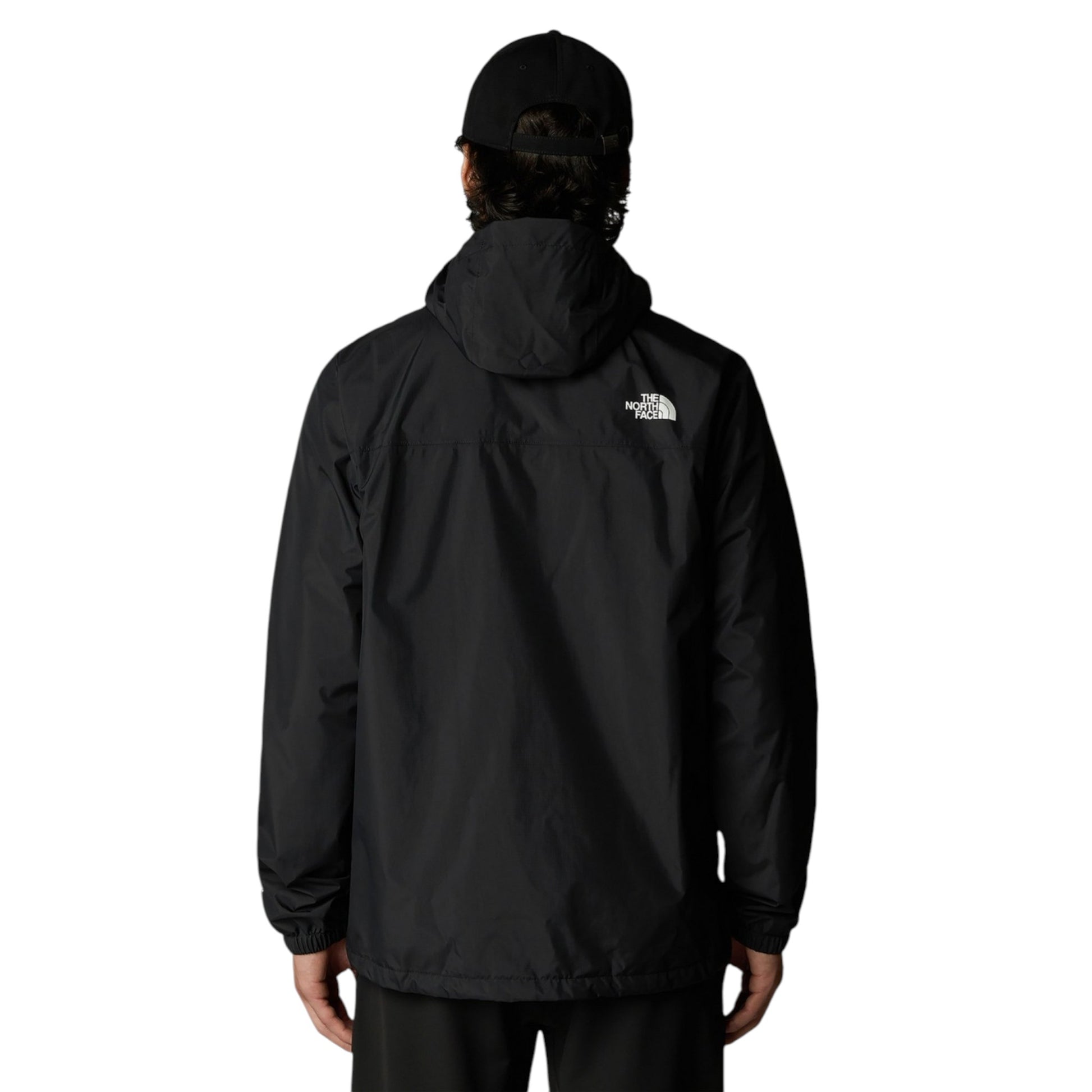 Person wearing a black jacket with a visible brand logo on the back, standing against a white background.