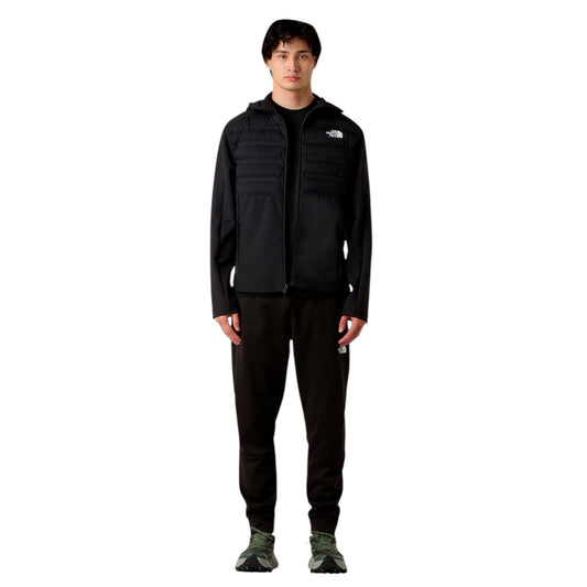 Person wearing a black jacket and pants with a logo on a white background