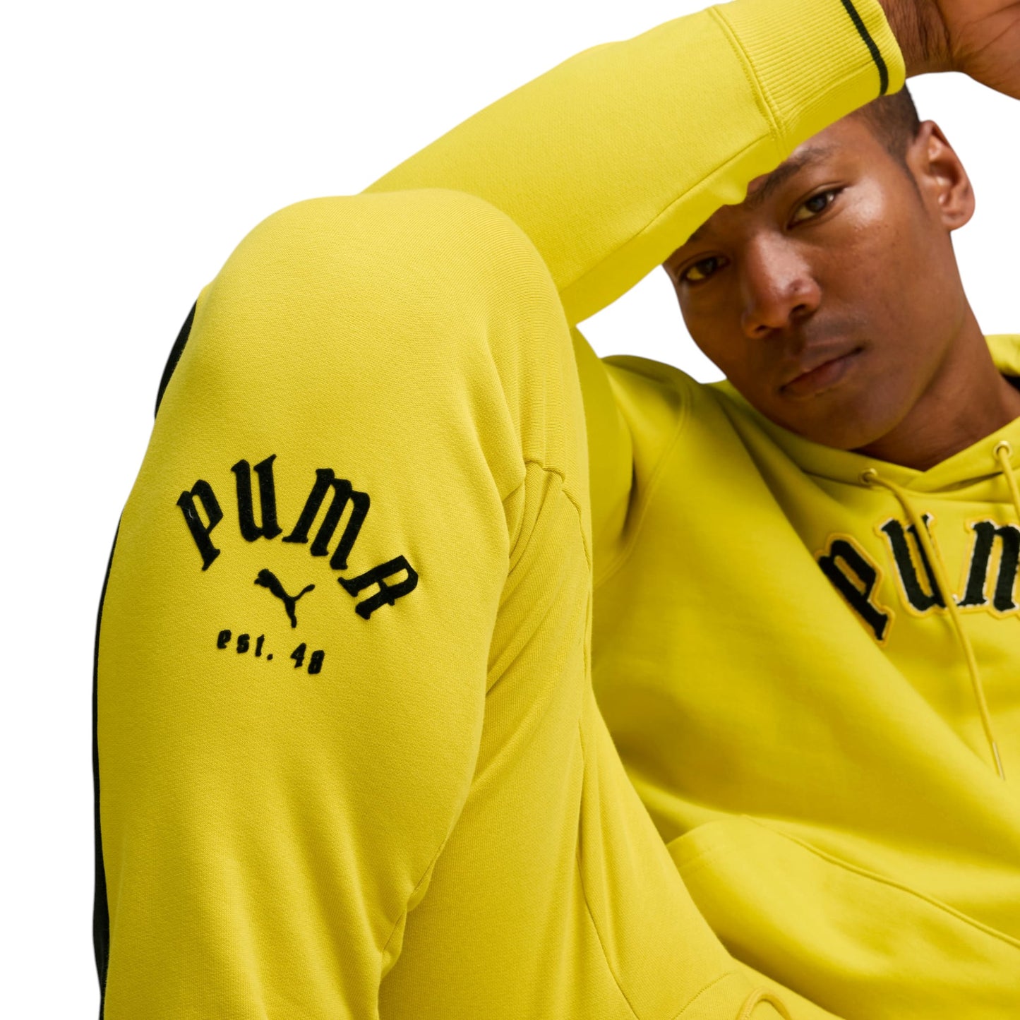Person wearing a yellow Puma hoodie and pants on a white background